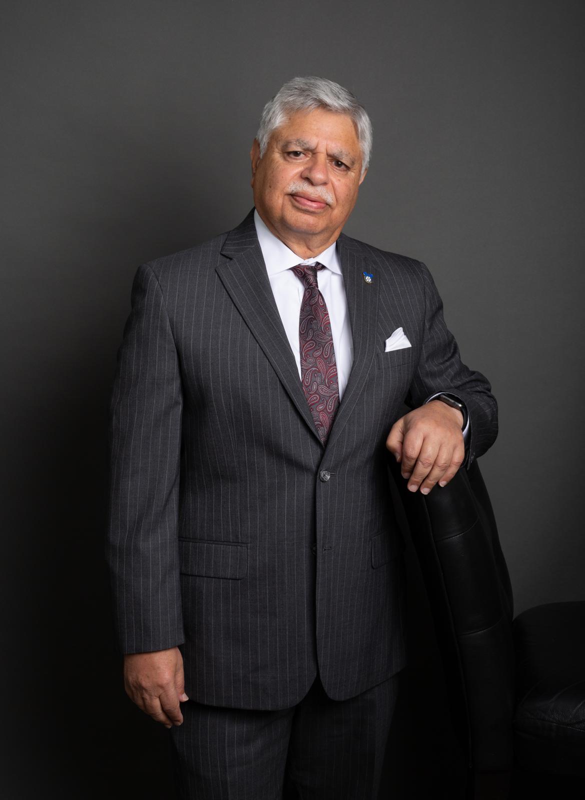 Khalid Muneer - Professional businessman in navy suit in bright well-lit modern office, confident posture, direct gaze
